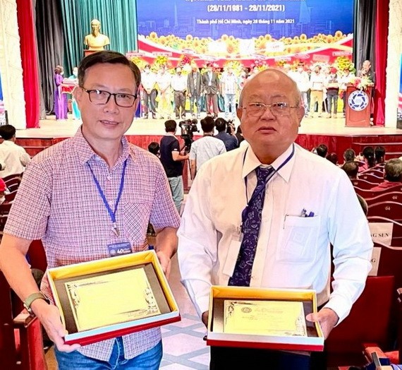 華人攝影家陳文儀及華人攝影會會長許勵程(右)領取紀念章。