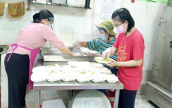 阮翠香（左）和慈善組成員將飯菜舀入盒子裡。