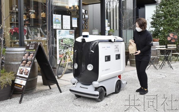 店員將便當裝入機器人的儲物箱內。（圖：共同社）