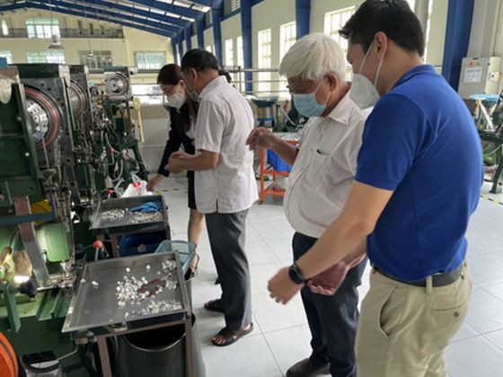 红心公司经理刘成发(右)引导本市纺织品成衣协会主席范春鸿参观公司车间。