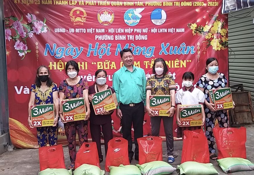 平新郡平治东坊常务副书记阮金龙（中）向环境困难的华人户赠送岁暮礼物。