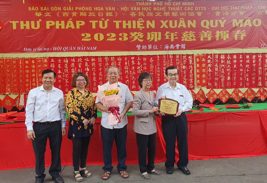 市祖国阵线委员会副主席刘金华（右二）、市各少数民族文学艺术协会副主席张四妹（左二）、华文《西贡解放日报》主编阮玉英（左一）向海南会馆赠送纪念章及鲜花以表谢意。