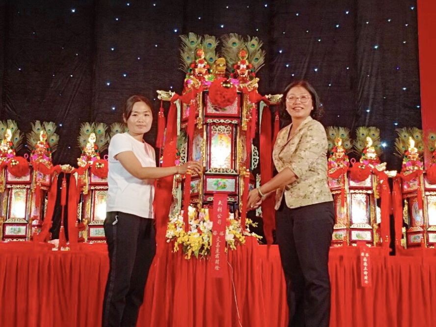 第五郡郡委书记黄玉女芳红向大利公司蔡美玲移交“文昌星君财灯”。