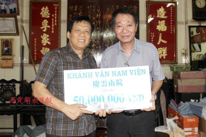 庆云南院住持周华邦（右）把赞助赠报经费交给本报主编阮玉英(红蓝)。