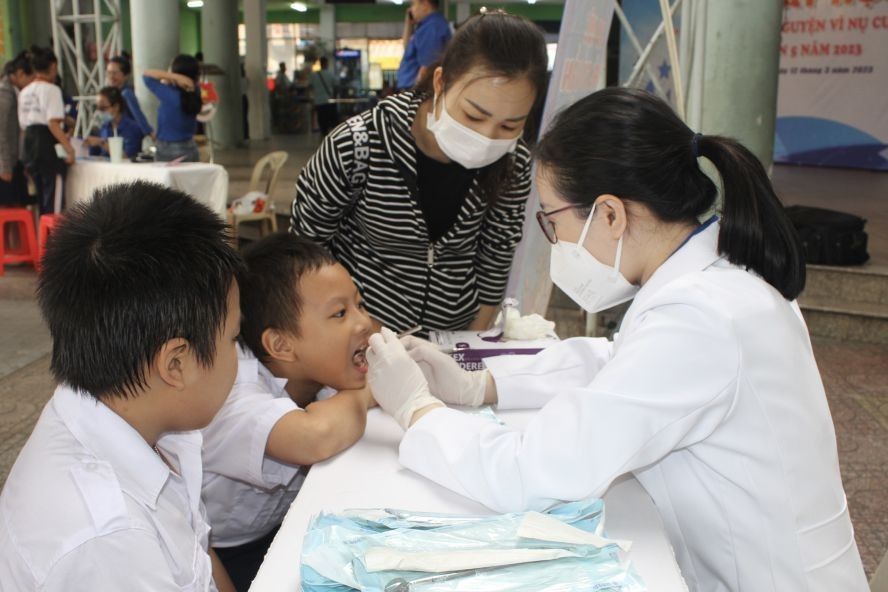 白衣志愿者为少儿做口腔检查。