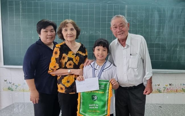 颍川双语学校副校长范氏绒(左二)代表董事会颁发奖金给千怡小妹妹。