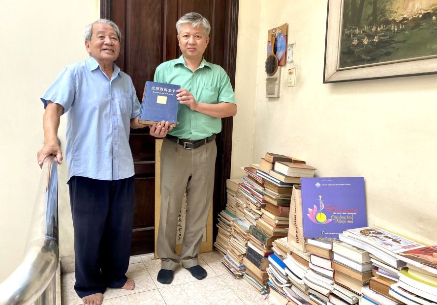 原主编怀雨（左）向编委黎曰孟雄转交书籍。
