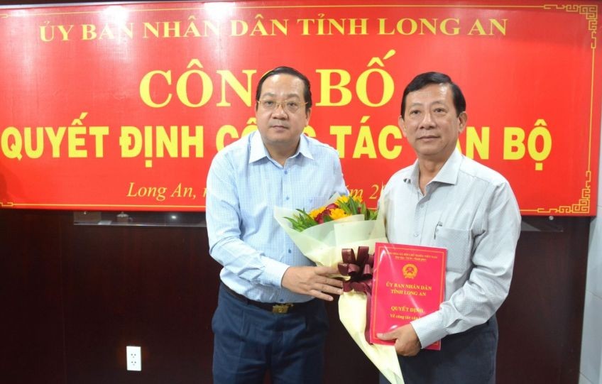 新闻与传播厅长阮伯伦（右）从隆安省人委会副主席阮明林手中接过人事委任《决定》和祝贺鲜花。（图：隆安报）