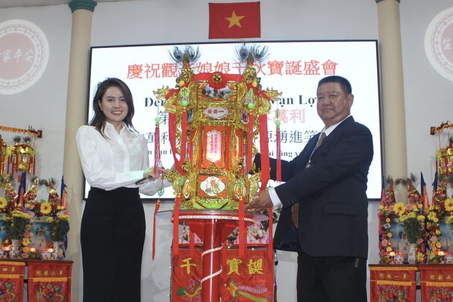 该庙副理事长梁耀明（右）向簪英移交第一圣灯。