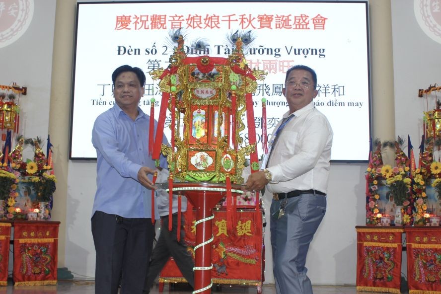 该庙副理事长邓贵仁（右）向邓奕敏移交第二圣灯。