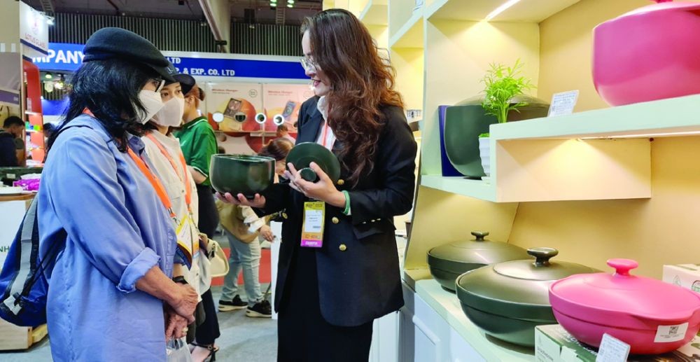 明隆一公司员工向参观者介绍新款养生瓷锅。