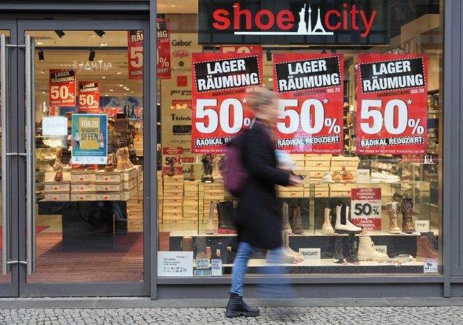 一名女子经过德国柏林的一家打折店铺。（图：新华社）