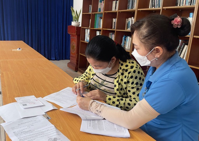 古芝县越南Samho有限责任公司工会干部指引劳工（左）按第6696号《决定》办理申请辅助卷宗。