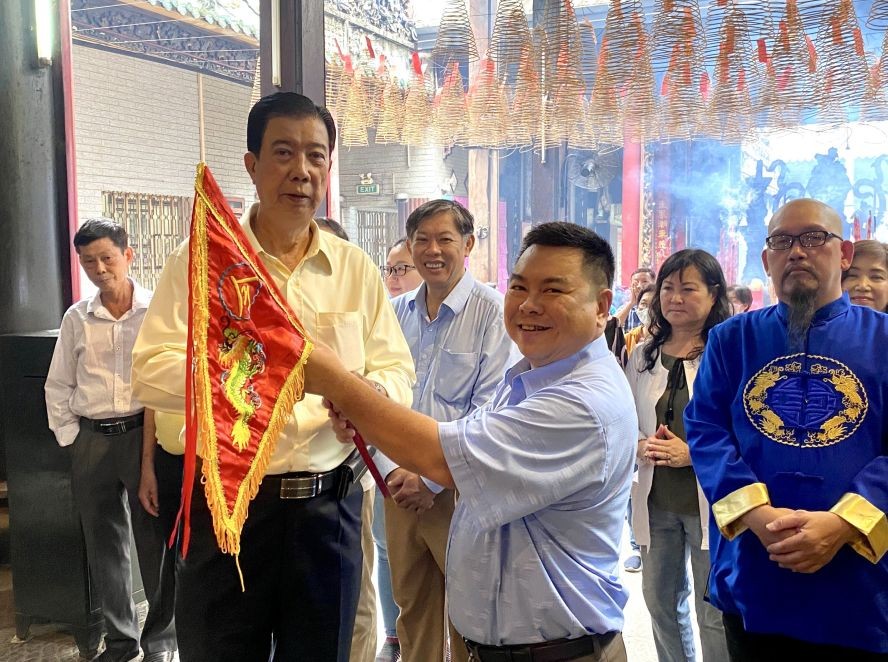 穗城会馆副理事长林海泉(左）将圣母令旗移交给统一粤剧团顾问会会长丁文森。