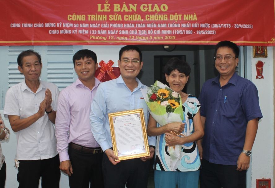 华文《西贡解放日报》编委文忠孝（中）和郡、坊领导祝贺卢月好大娘（右二）。