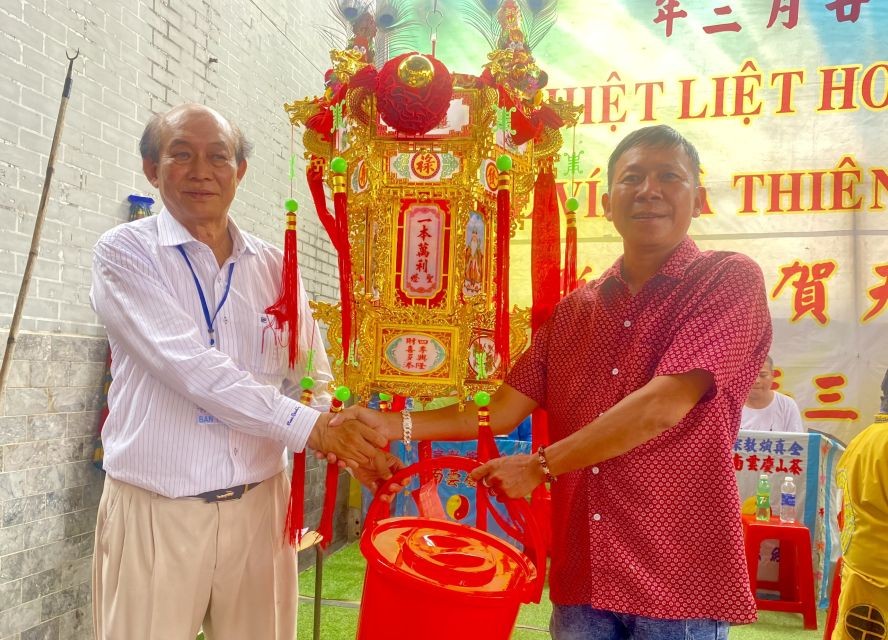 群宾会馆值理会主席曾业文（左）将第一圣灯移交得主黄英瑞，由父亲黄泽邦代领。