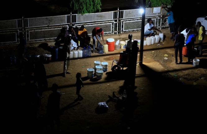 五月份喀土穆停电期间，人们聚集在一起利用发电机的光线取水。（图：路透社）