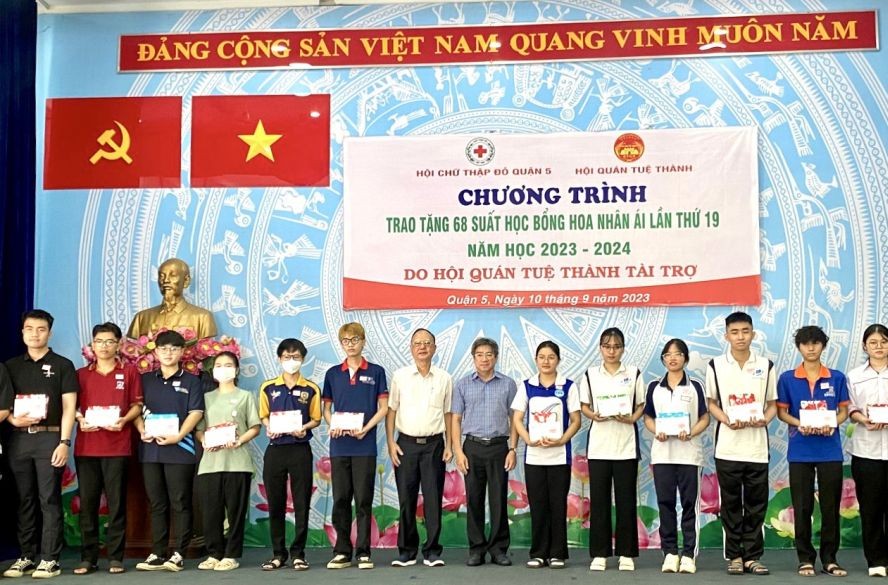 第五郡人委会副主席阮武春奇；第五郡红十字会副主席、穗城会馆理事长卢耀南向贫困好学学生颁发助学金与礼物。