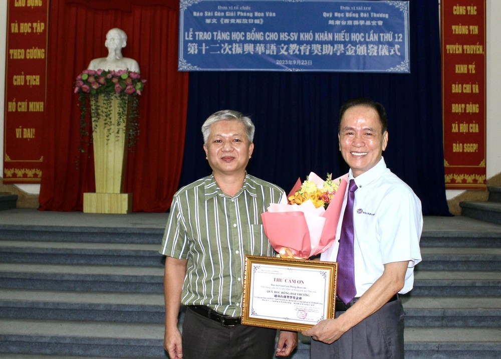 华文《西贡解放日报》编委黎曰孟雄（左）向越南台商奖学金基金会董事长苏建源赠送鲜花与感谢状。