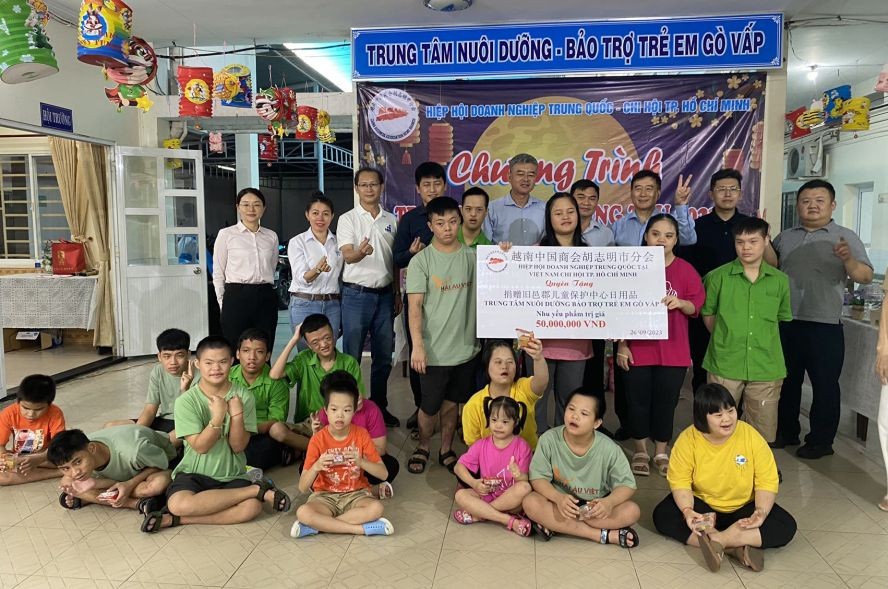 越南中国商会胡志明市分会爱心团与旧邑郡儿童辅育中心病童及工作人员合照。