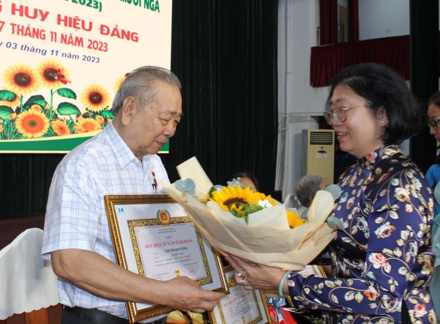 第五郡郡委书记黄玉女芳红向华人革命老前辈孙盛强颁发55年党龄纪念章。