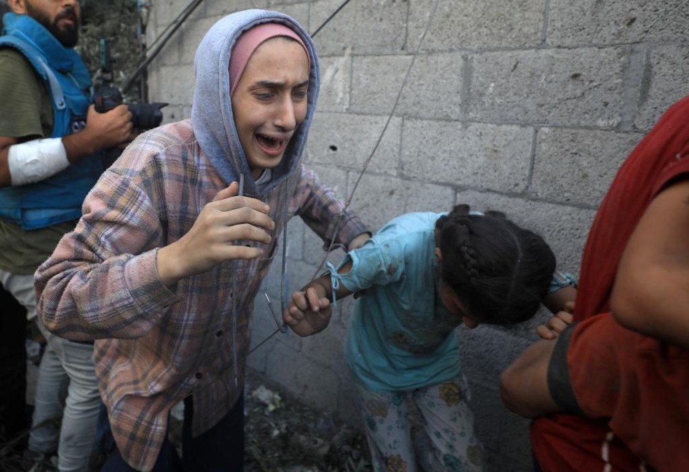 6日，人们从加沙地带中部地区一处被炸难民营逃离。（图：新华社）