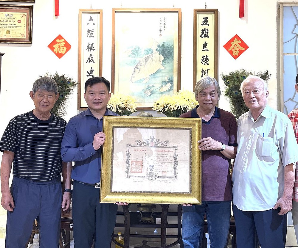 陈马尚收藏家（左三）向笔者赠送保大王1942年御赐的证书。左一为李克柔画家，右一为邬有发书法家。