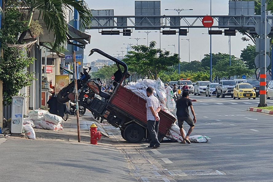 运送建材的三轮车在第五郡武文杰街人行道上前轮飃起。
