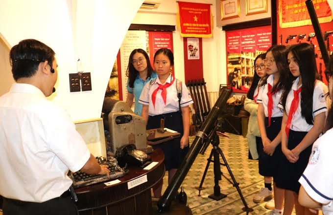 第一郡阮攸初中学校学生聆听关于西贡-嘉定别动博物实物意义的介绍。