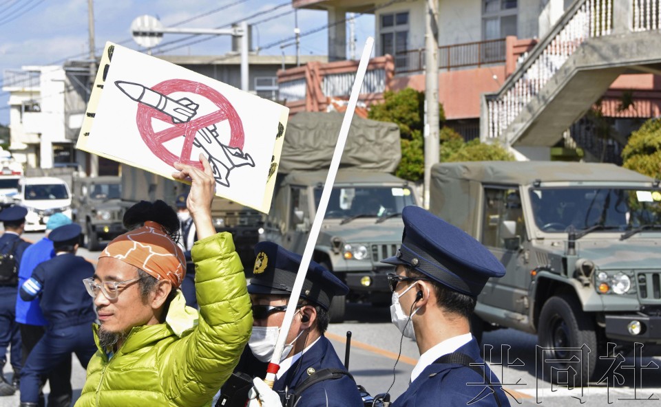 抗议人群对着开往自卫队胜连分屯地的车队举起标语牌。3月10日上午摄于冲绳县宇流麻市。（图：共同社） 