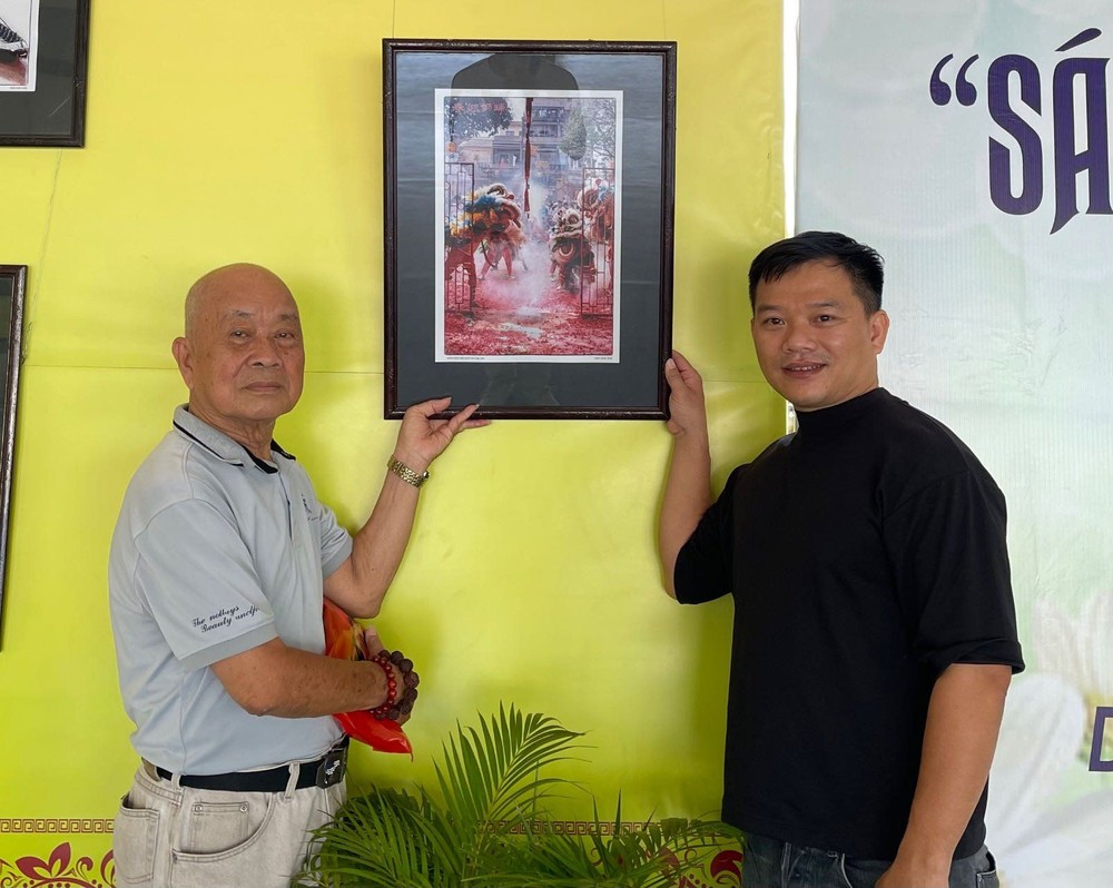 周经春（左）向笔者赠送《瑞狮迎春》作品。