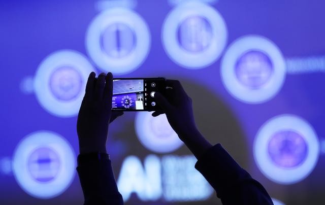 2024年2月27日，在西班牙巴塞罗那举行的2024年世界移动通信大会上，与会者在“算力网络：智能网络赋能智慧世界”专题论坛上拍摄关于AI内容的幻灯片。（图：新华社）