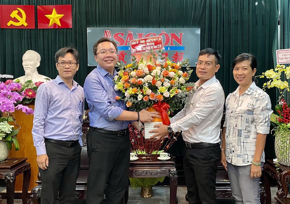 第五郡第一坊人委会主席武明哲向本编委文忠孝（右二）赠送鲜花祝贺。