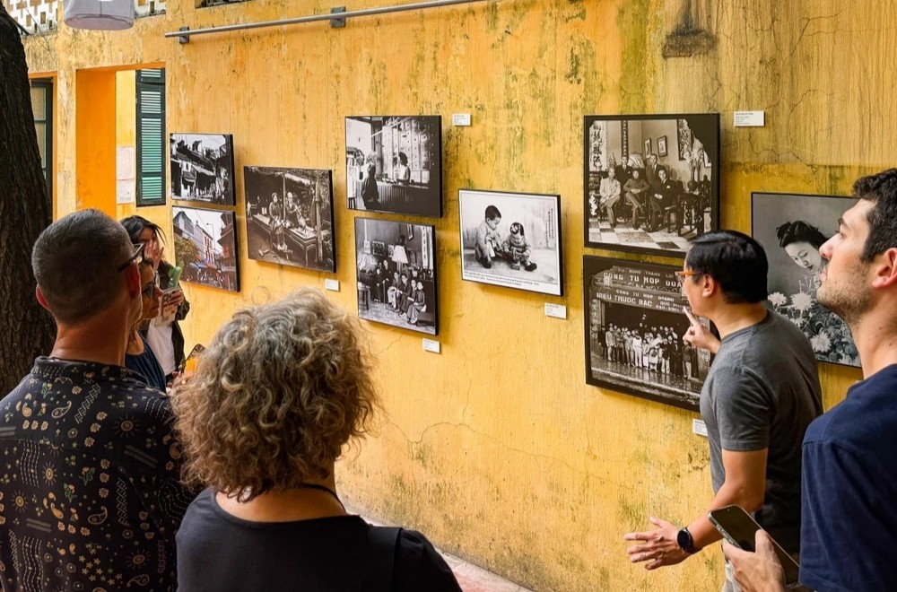 外国游客在河内古街参观图片展。