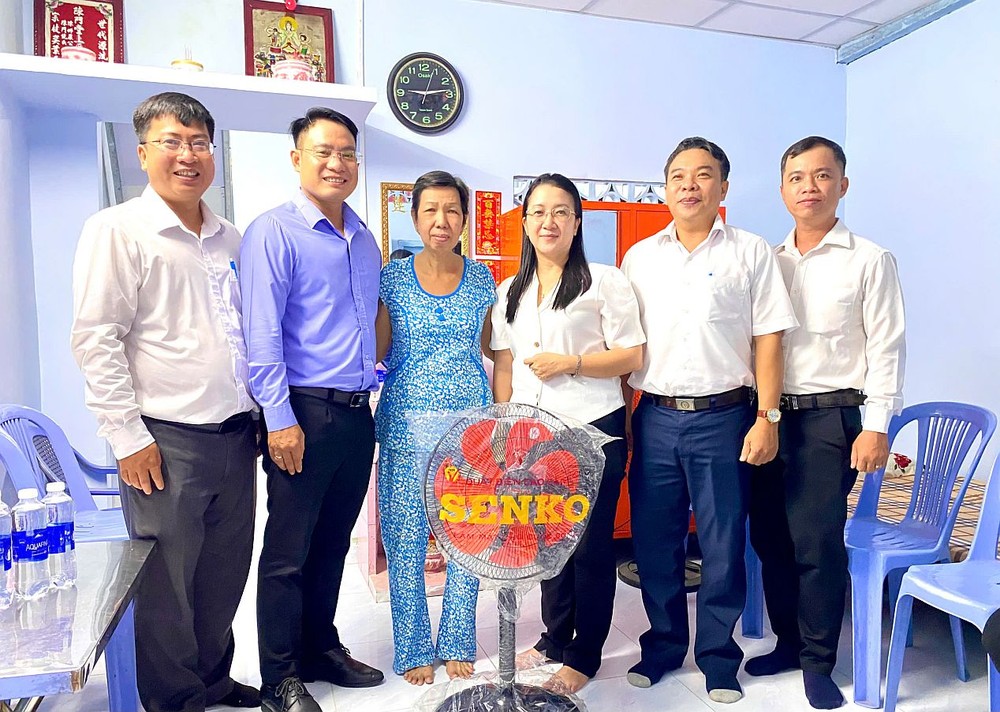 华文《西贡解放日报》、第十二坊党政领导向户主陈秀萍(左三）祝贺和赠送礼物。