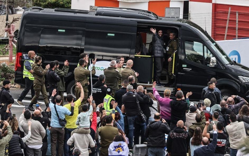 2月22日，在佩塔提克瓦一处医疗中心的门口，获释的以色列被扣押人员向人群致意。（图：新华社）