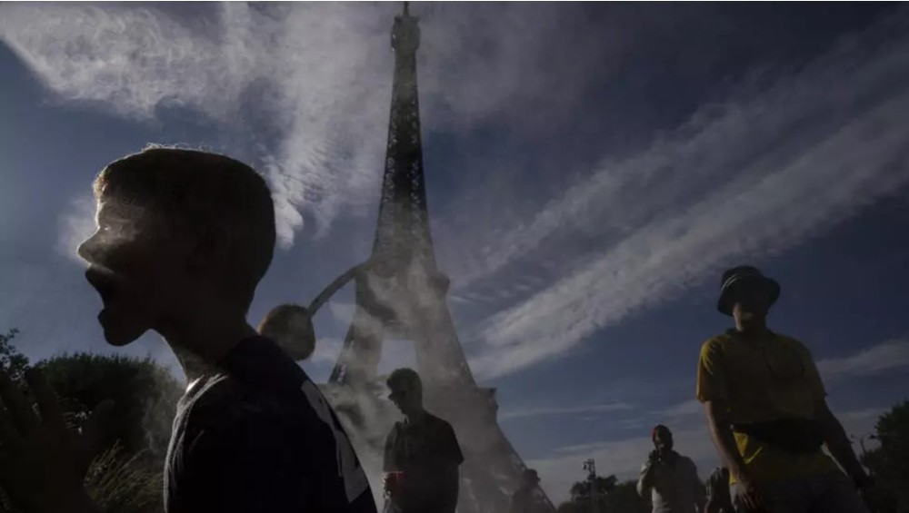 图为2024 年法国巴黎夏季奥运会期间，人们在埃菲尔铁塔外的薄雾下乘凉。（图：AP）