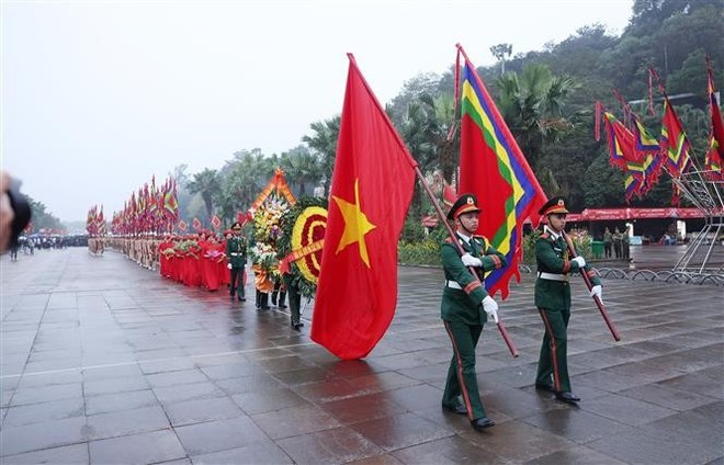 越南人民军官兵们手持国旗、幡旗和写有"世代铭记雄王建国之功"的花圈。（图：越通社）
