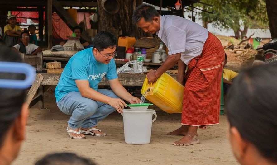 在灾情严重的曼德勒，儿基会工作人员正与当地村民向社区民众示范净水片的使用方法。（图：联合国）