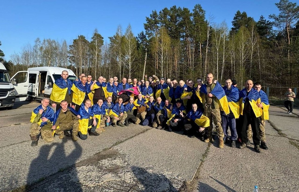 获释的乌克兰军人披上国旗合照。（图：路透社）