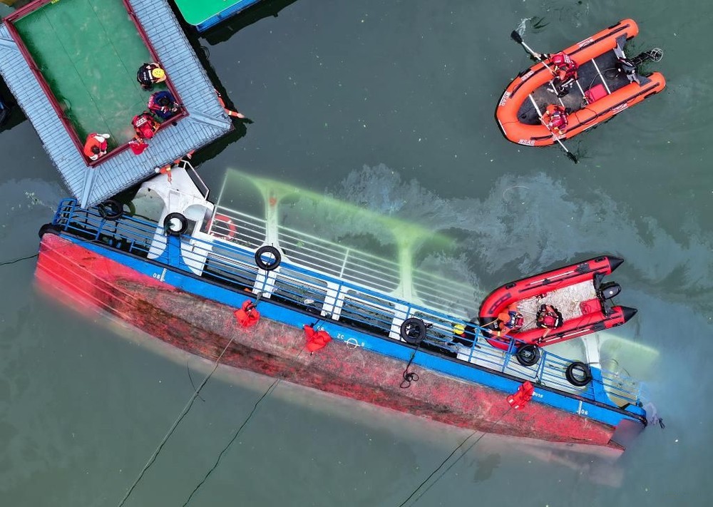 救援人员在对倾覆船只进行搜救(无人机照片)。（图：新华社）