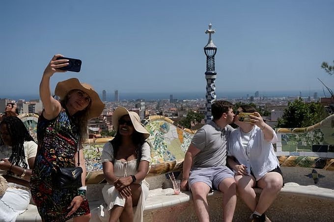 游客们在巴塞罗那自拍，活动人士在此召开了一场关于过度旅游的会议。（图：路透社）
