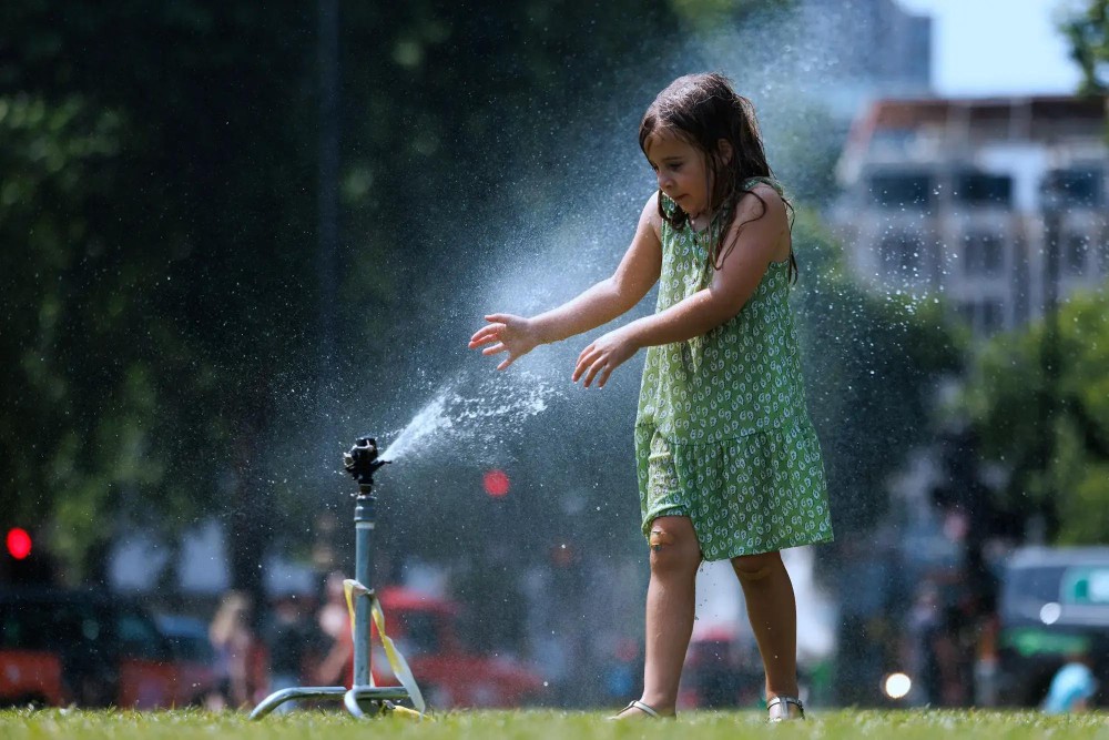 一名女孩把水喷洒到脸上解暑。（示意图：互联网）