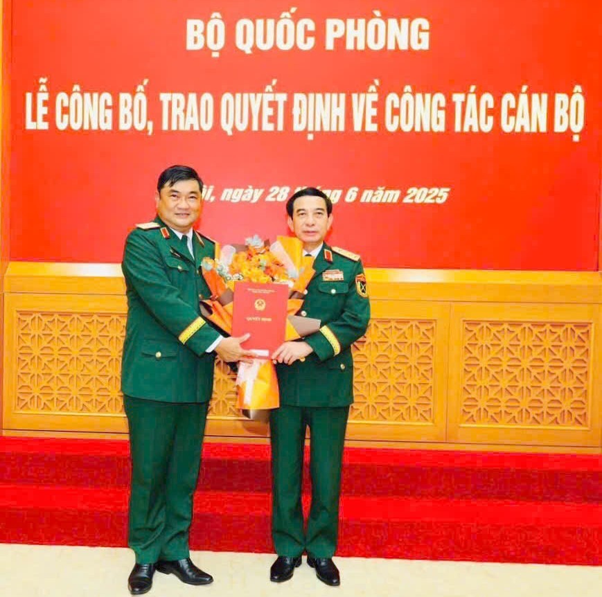 第七军区司令黎春世少将（左）从国防部长潘文江大将手中接过《决定》和祝贺鲜花。