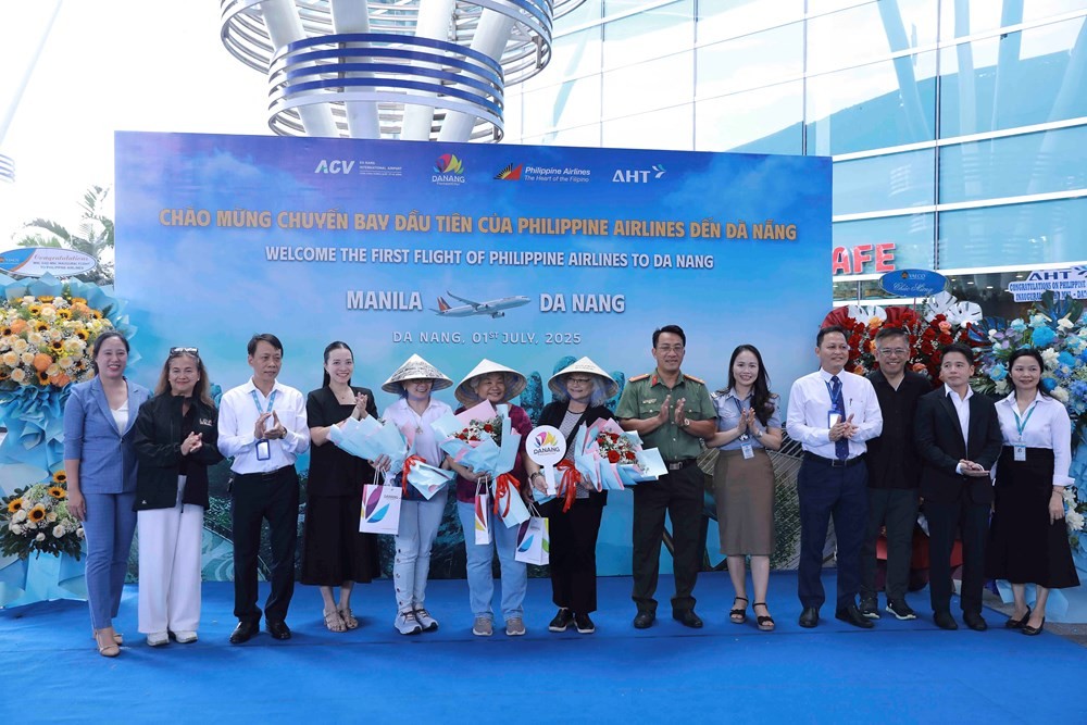 岘港市文体与旅游厅领导向PR585航班上的旅客赠送鲜花和纪念品。