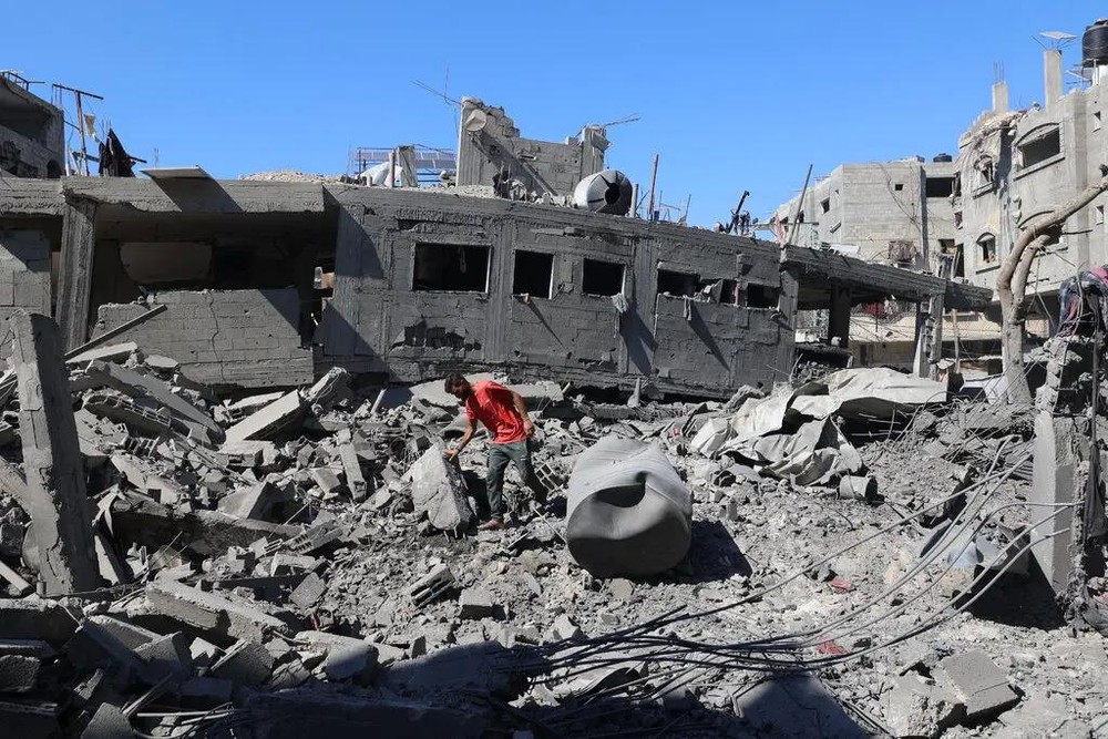 一名男子在以色列袭击加沙中部后视察受损情况。这场战争已造成数万巴勒斯坦人死亡，并将大部分领土夷为平地。（图：Getty Images）