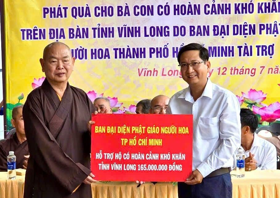 释慧功和尚向永隆省新乂乡人委会副主席文功智移交救济品。