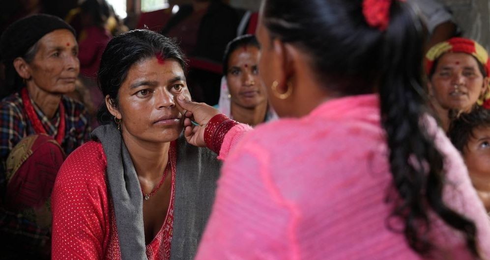 一名女性社区卫生志愿者通过检查尼泊尔农村一名妇女的下眼睑是否颜色苍白来筛查其是否患有贫血。（图：联合国）