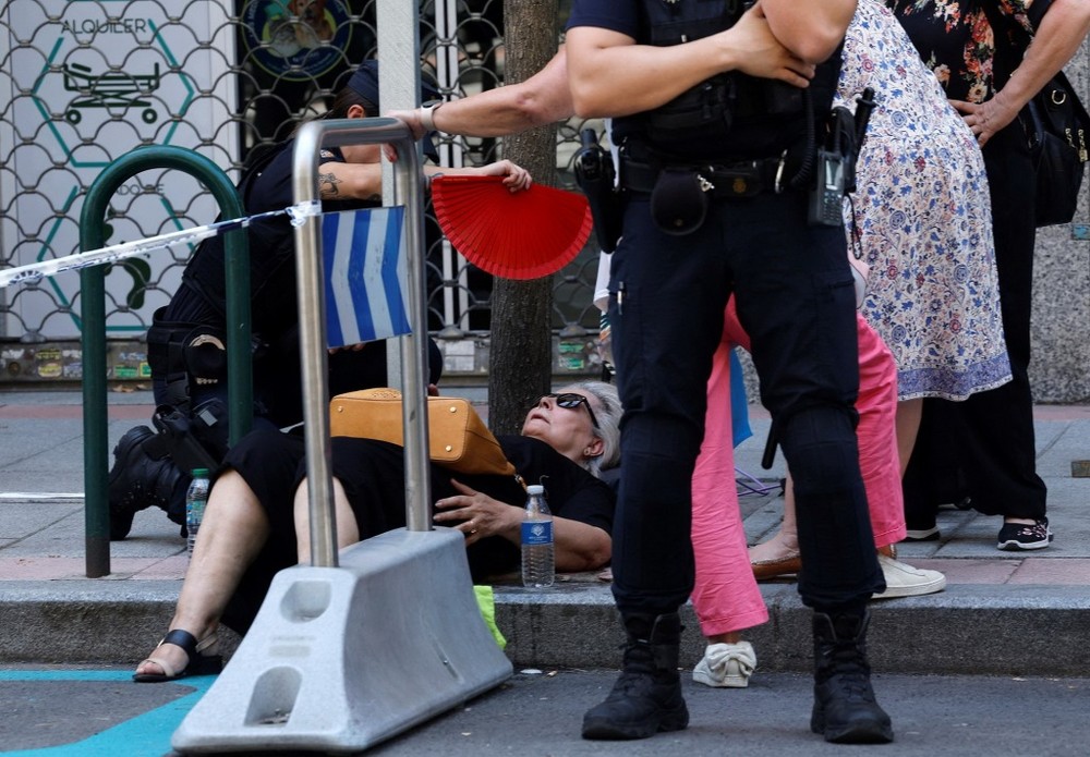 当地时间2025年7月5日，西班牙马德里，一名女子在街上因中暑晕倒，警察为她扇风降温。（图：互联网）