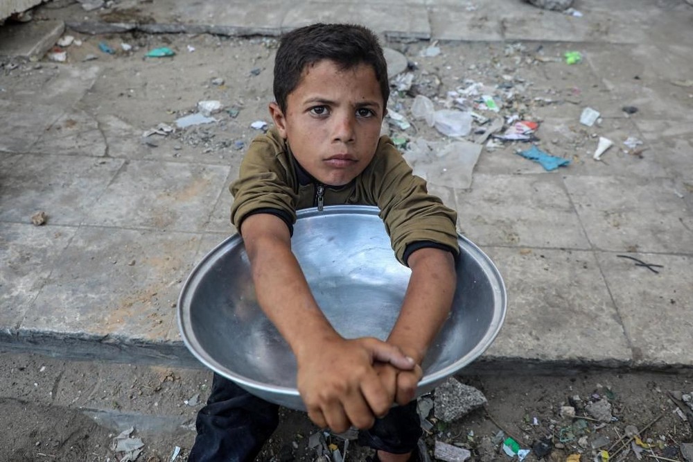 7月14日，一名儿童在加沙城的一处食物分发点等待领取免费食物。（图：新华社)